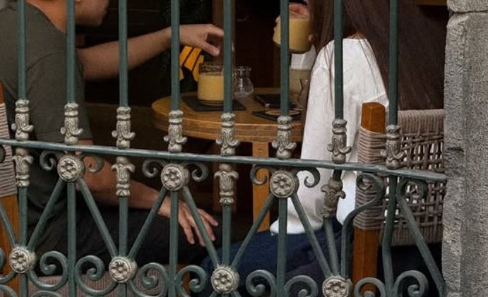 Clientes tomando café tras la herrería colonial de la fachada