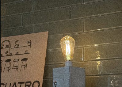 Foco de filamento encendido junto al letrero de La Cuatro