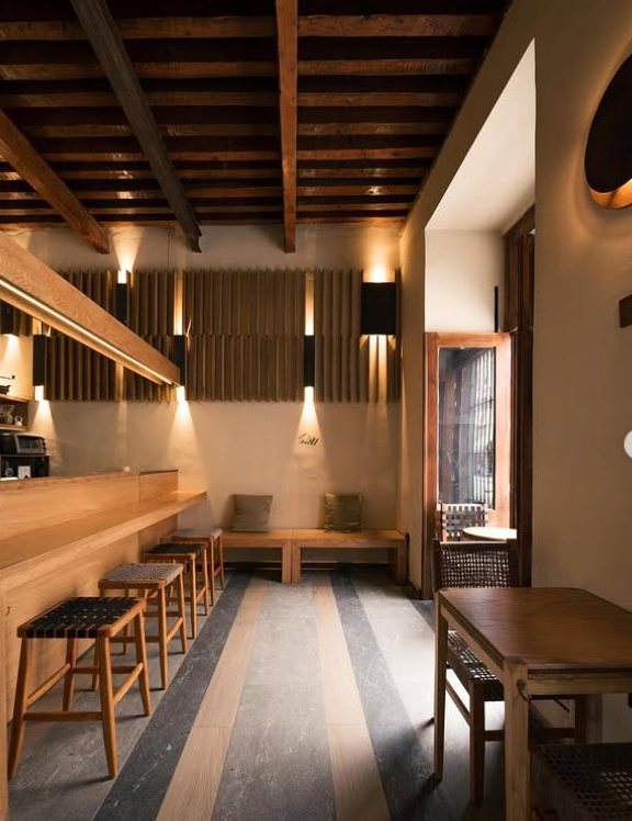 Interior de La Cuatro con vigas de madera y muros cálidos iluminados