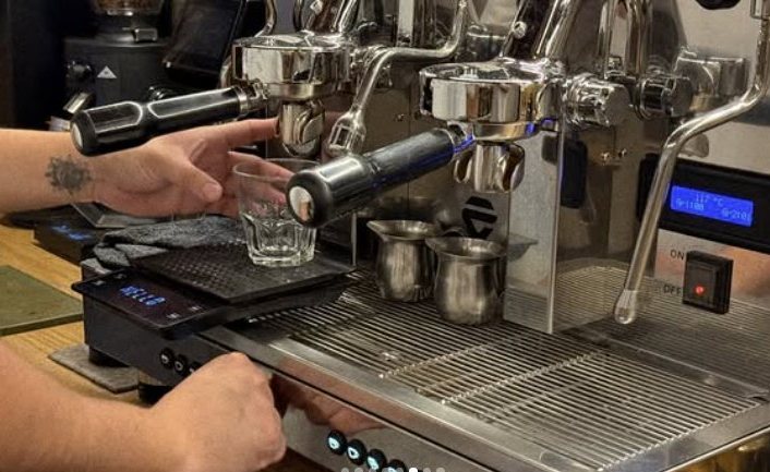 Barista extrayendo espresso en la máquina de dos grupos