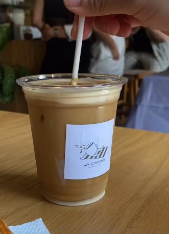 Iced latte con etiqueta de La Cuatro sobre mesa de madera