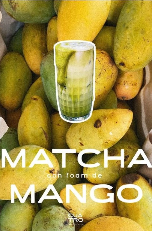 Vaso de matcha con foam de mango sobre un fondo de mangos frescos